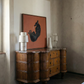 Wooden sideboard with a painting of a dog on an orange background in a room with textured walls. Black dog – Contemporary Animal Canvas Art | Luxury Wall Decor | Brume Art | Luxury Wall Decor | Large Canvas Wall Art | Oversized Wall Hanging-Brume art