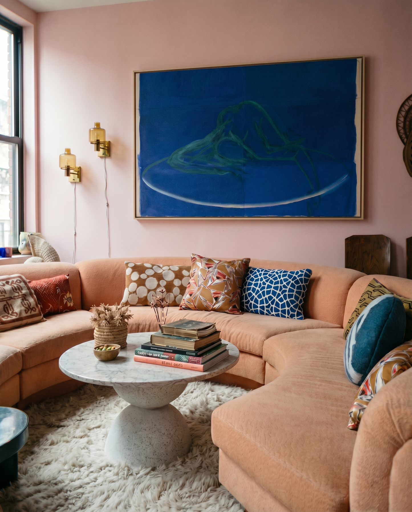 Living room with a pink wall, sectional sofa, and abstract painting.