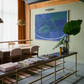 Modern interior with a gold console table, books, and a painting on a green wall.