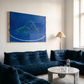 Modern living room with dark blue sofa, abstract painting, and marble coffee table.