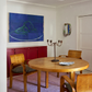 Dining room with wooden table and chairs, red cabinet, and abstract art on the wall.