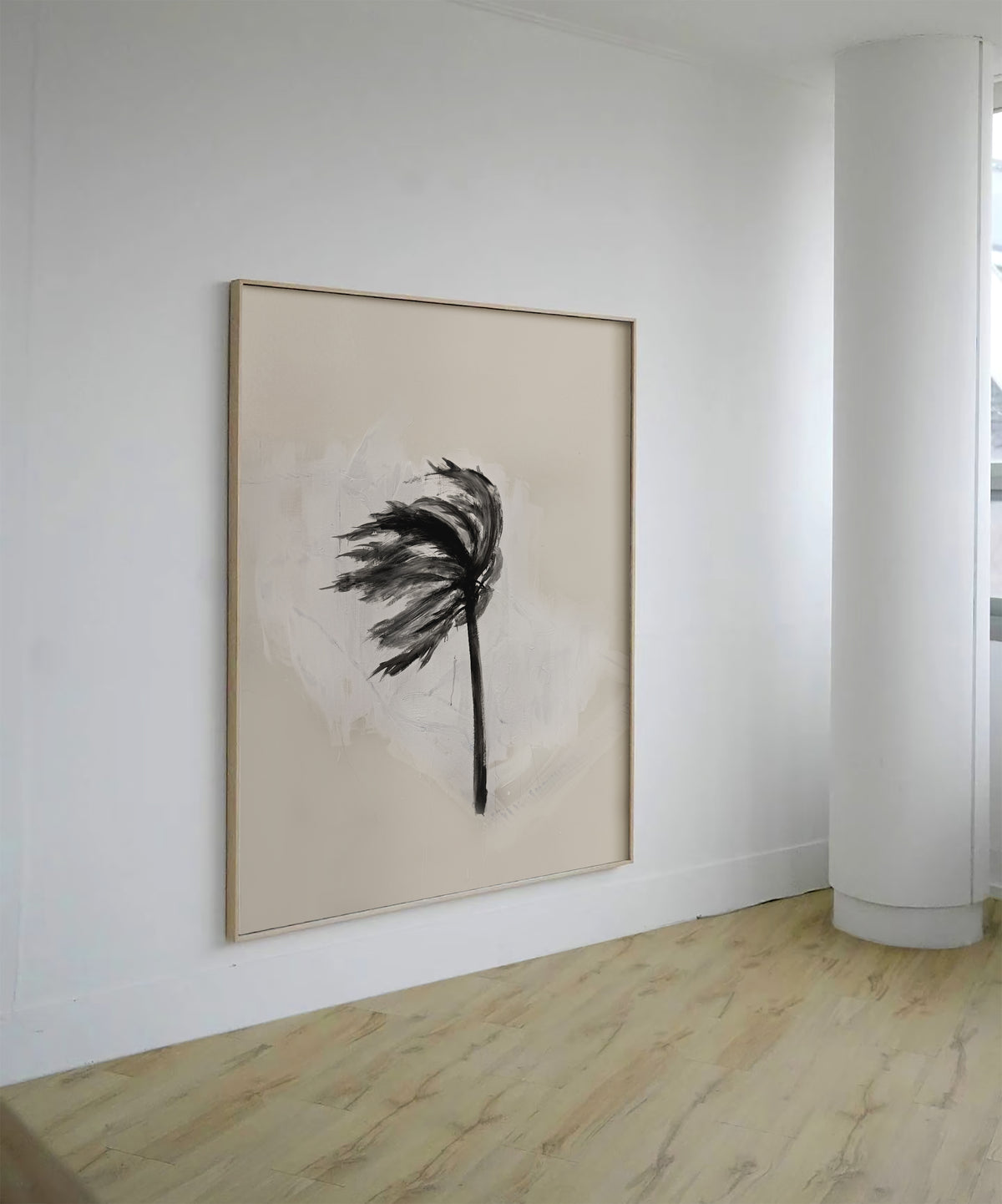 A framed abstract wall art print hangs on a white wall in a minimalist room with light wood flooring. The artwork features a black palm-like silhouette over a soft beige and off-white textured background, enclosed in a thin light wood frame.
