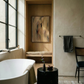 Bathroom interior with a bathtub, stool, and wall art. Abstract painting with brown and black brush strokes on a beige background Field Yellow 2 – Landscape Canvas Wall Art | Premium Luxury Print | Brume Art