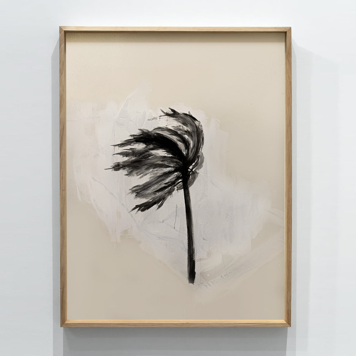 A framed abstract art print featuring a black brushstroke palm frond on a textured beige and white background, enclosed in a light wood frame and mounted on a white wall.