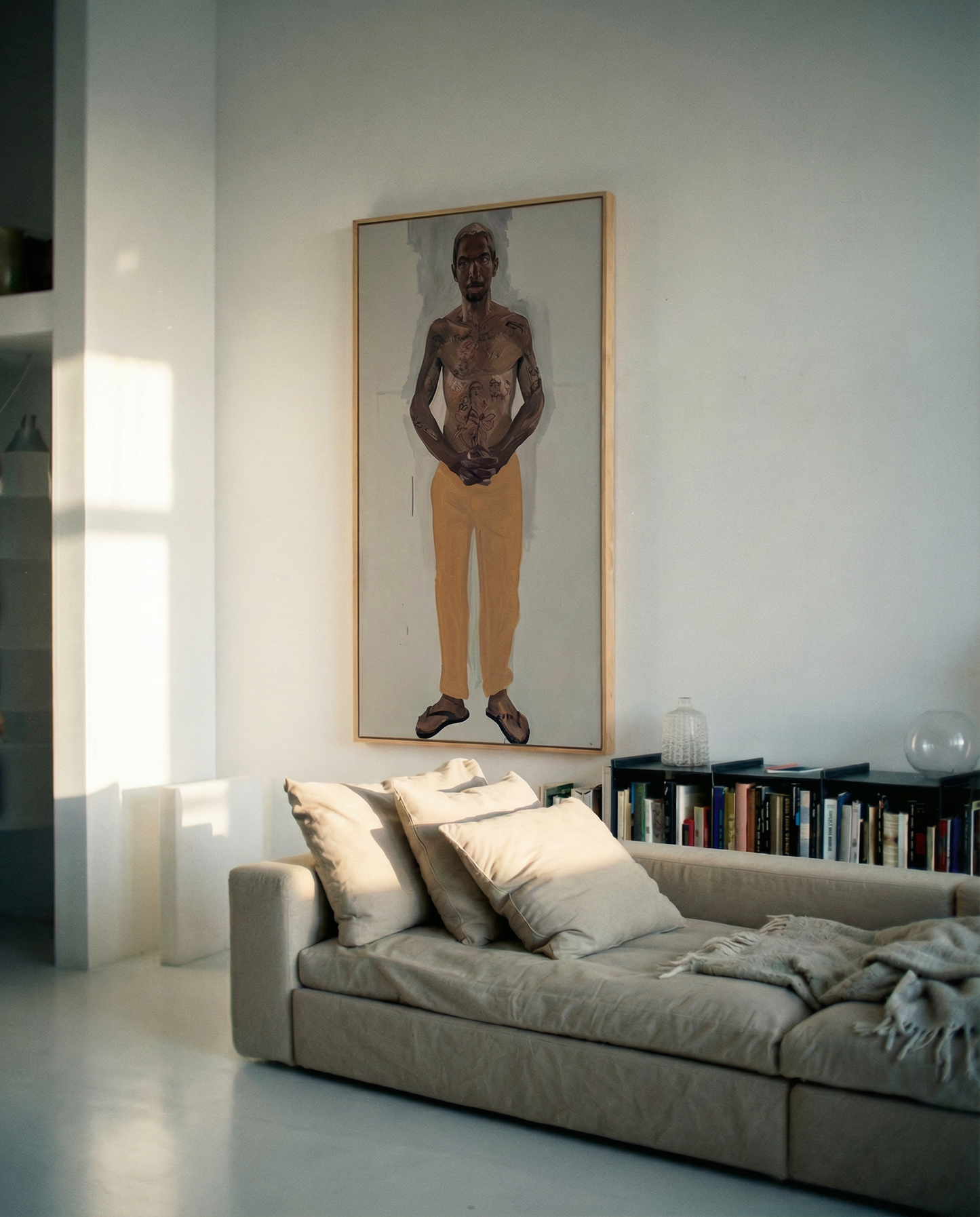 Living room with a gray sofa, books on a shelf, and a large framed portrait of a man on the wall. Fisherman of manila-Figurative Canvas Wall Art | Premium Luxury Print | Brume Art | Luxury Wall Decor | Large Canvas Wall Art | Oversized Wall Hanging-Brume art